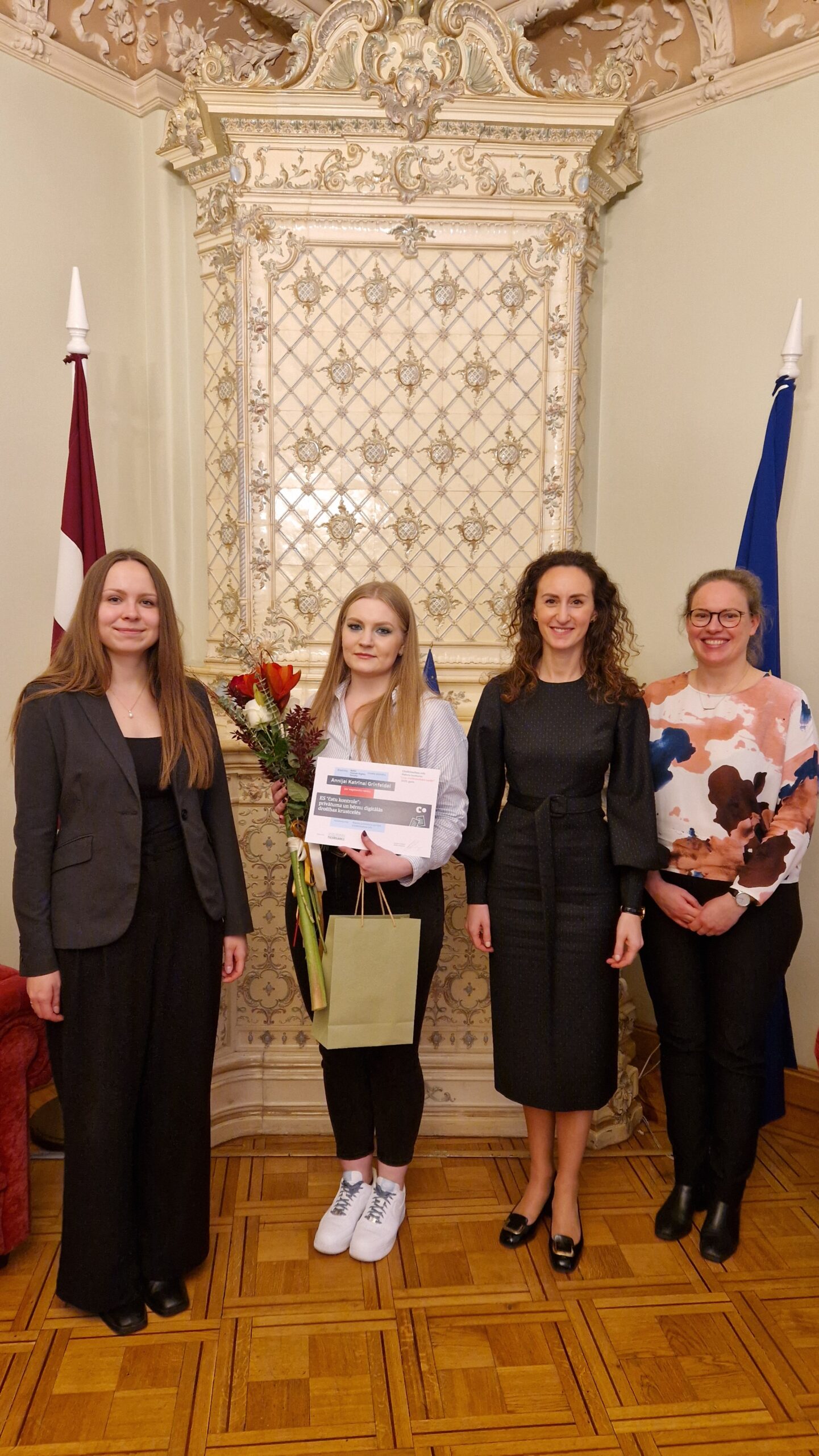 Karina Palkova, Arina Melse un Ieva Šņepste sveic atzinības ieguvēju Anniju Katrīnu Grīnfeldi