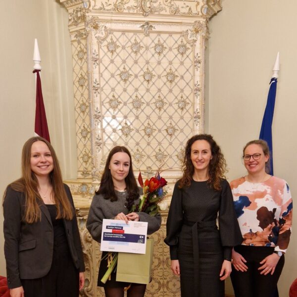 Karina Palkova, Arina Melse un Ieva Šņepste sveic atzinības ieguvēju Emīliju Petrovu