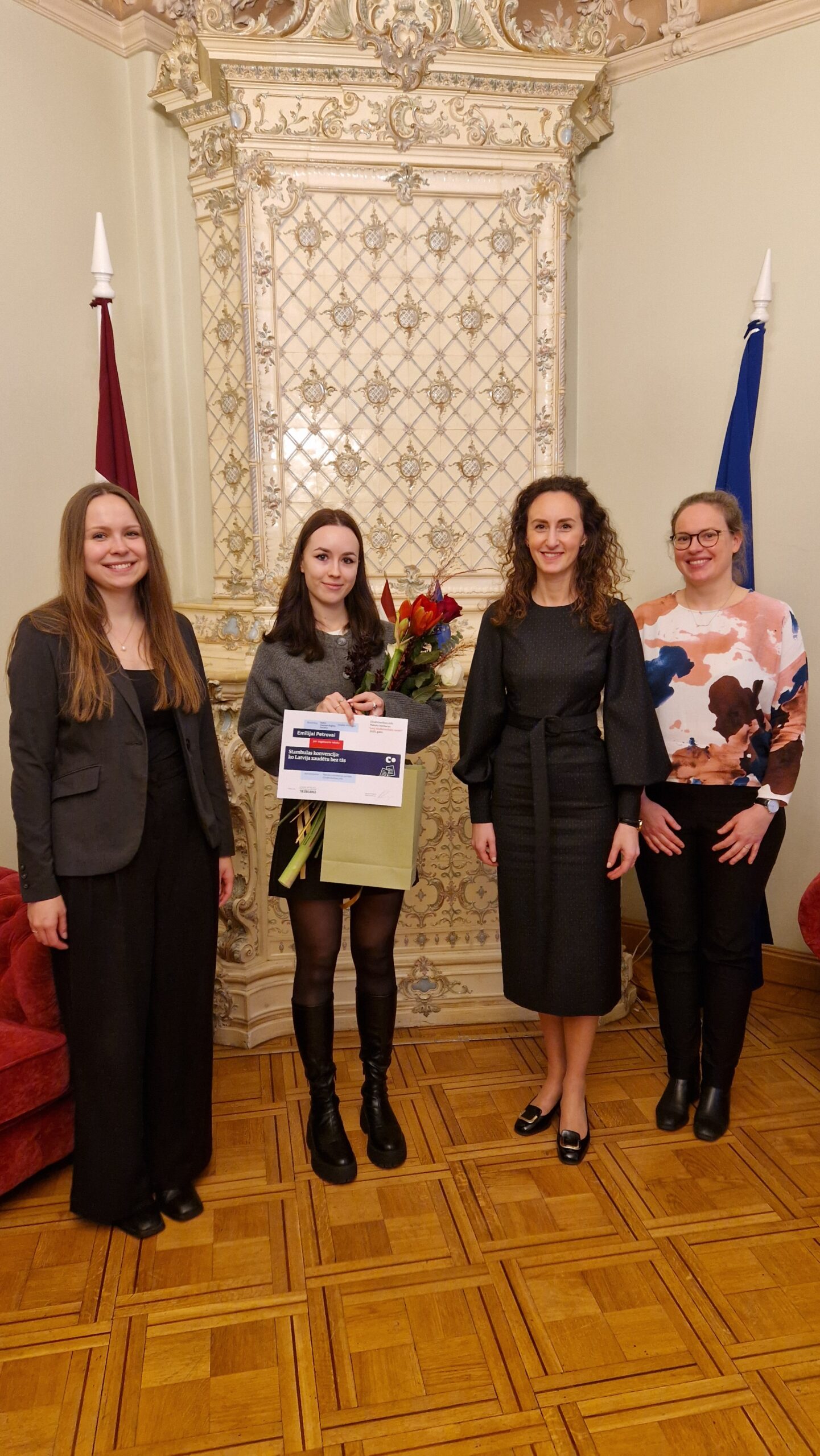 Karina Palkova, Arina Melse un Ieva Šņepste sveic atzinības ieguvēju Emīliju Petrovu