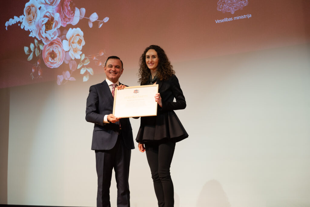 Attēlā veselības ministrs Hosams Abu Meri un tiesībsardze Karina Palkova, saņemot no ministra atzinības rakstu.